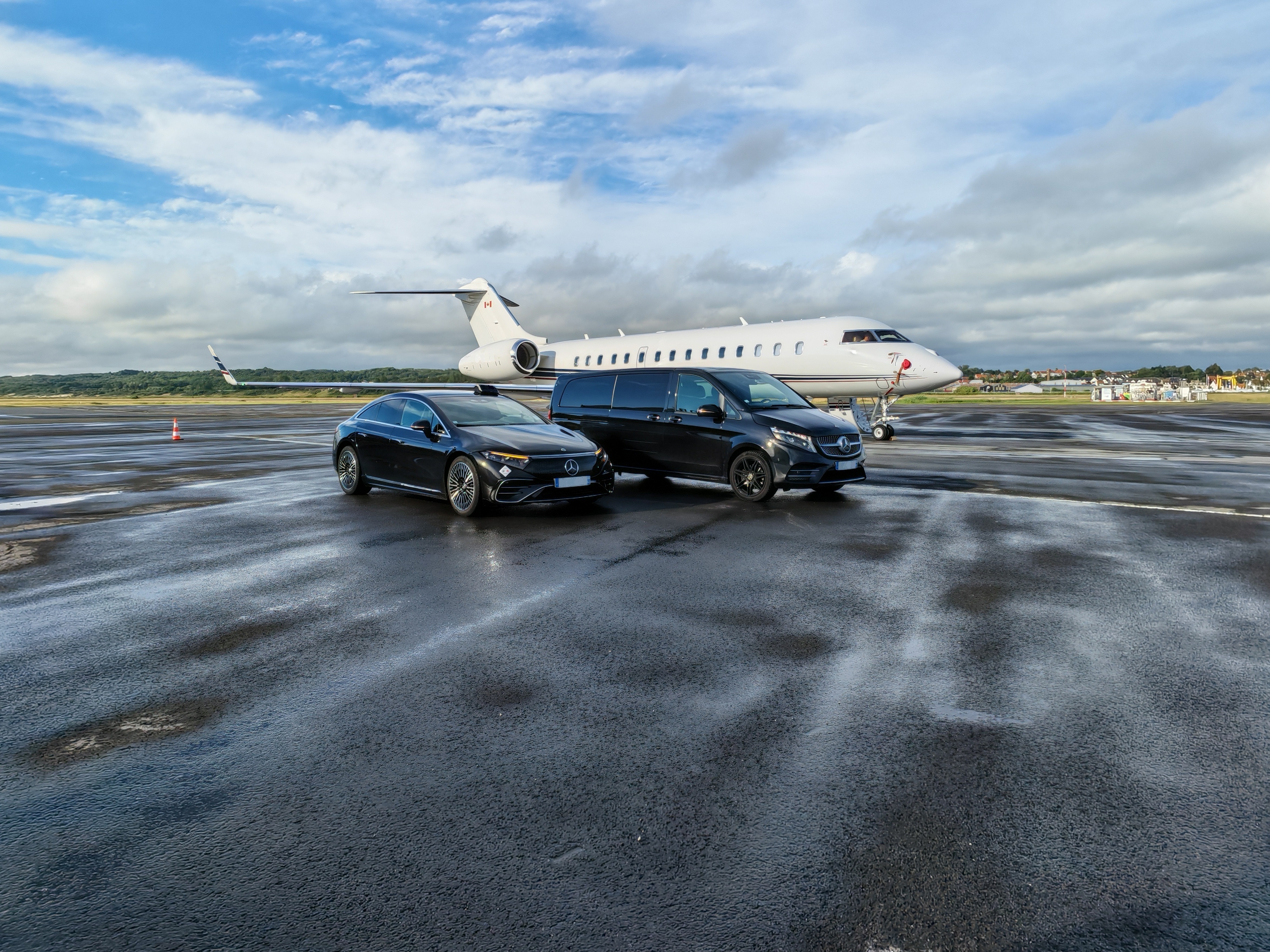 Mercedes EQS et Classe V noires garées sur le tarmac devant un jet privé