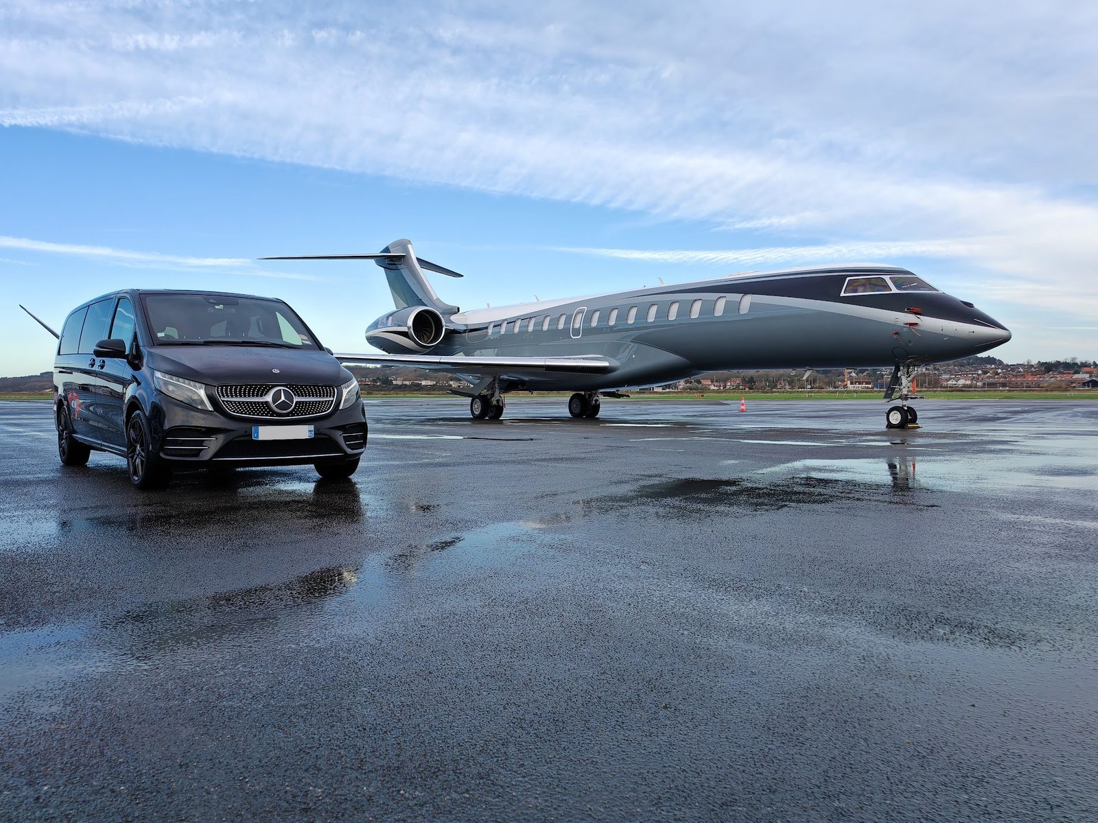 Mercedes Classe V noire garée à côté d'un jet privé sur le tarmac