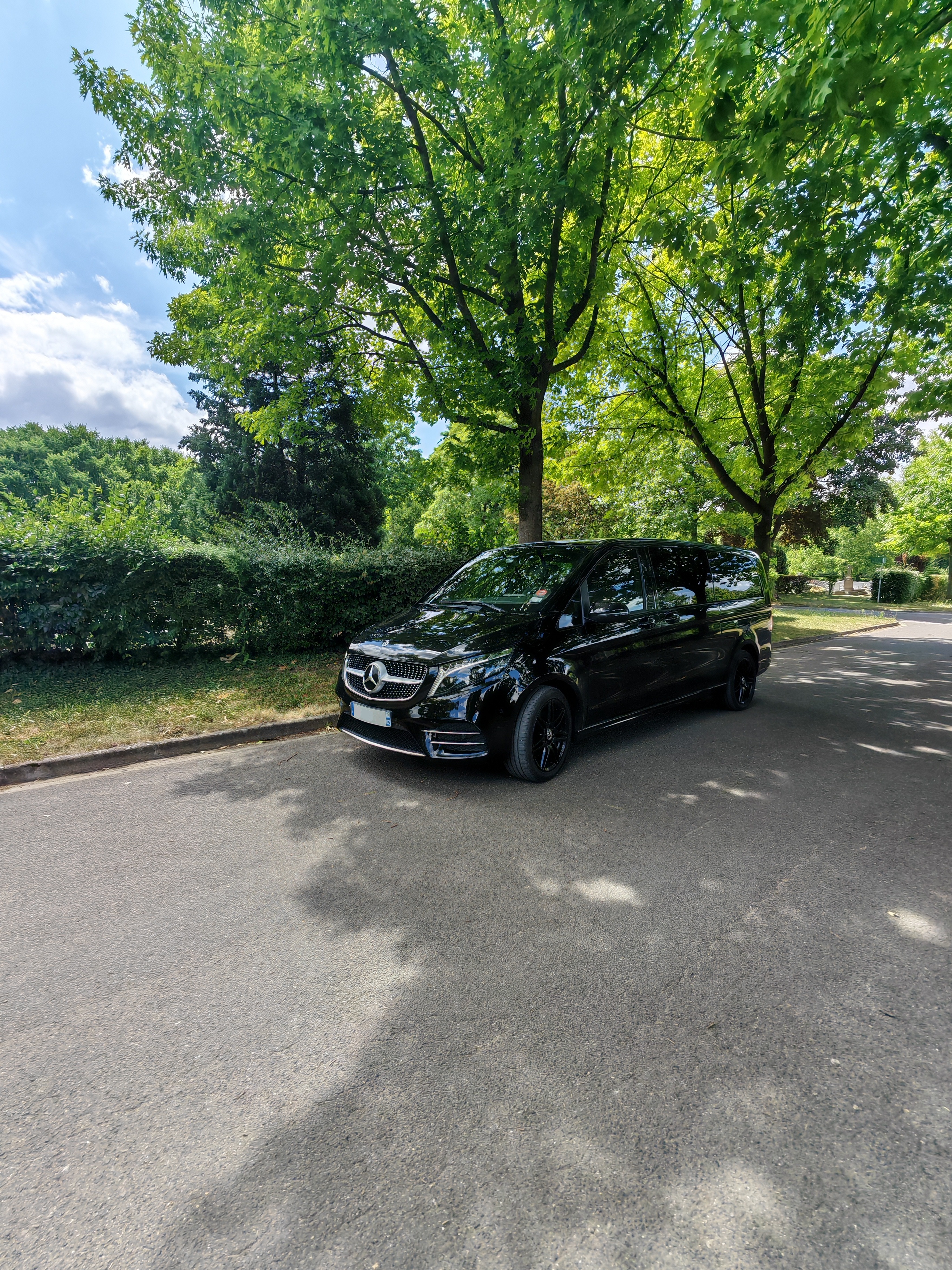 Mercedes Classe V noire garée sous les arbres en été